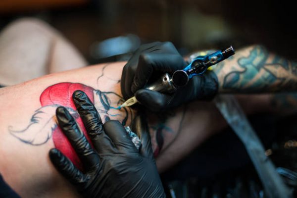 Professional artist making tattoo in salon. Close-up view of male hand making tattoo